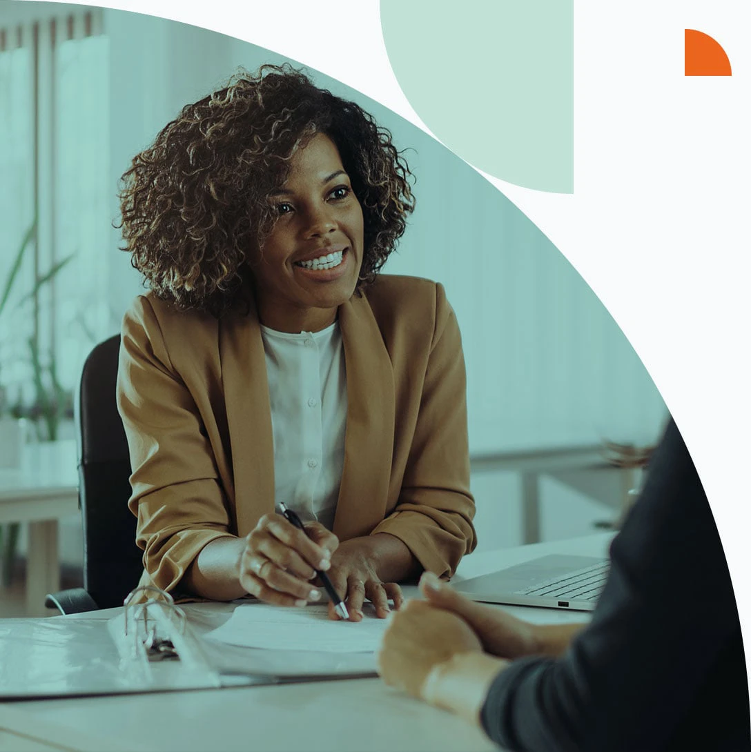 Frau unterhält sich an einem Tisch mit einer weiteren Person